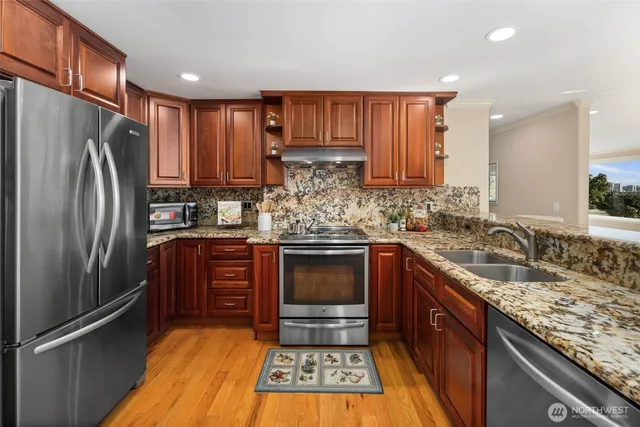 a kitchen with granite countertop stainless steel appliances a refrigerator and a sink