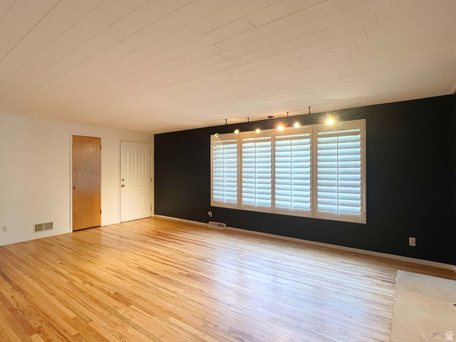 3138 Jean Street Magna, UT 84044 - Photo 5 of 26 Bright interior space featuring wood-finish flooring, a painted plank ceiling, and a prominent window array with louvered shutters