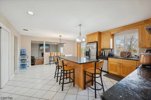 a dining hall with stainless steel appliances kitchen island granite countertop a table and chairs in it