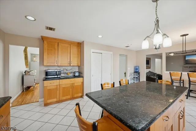 a kitchen with stainless steel appliances granite countertop a stove top oven a sink a dining table and chairs with wooden floor