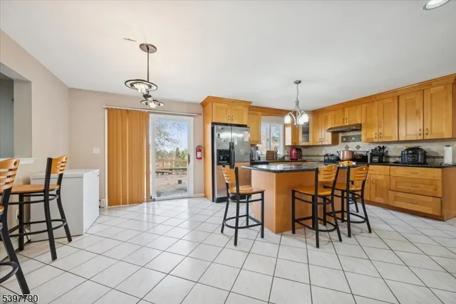 a kitchen with stainless steel appliances kitchen island granite countertop a refrigerator a stove a microwave oven with white cabinets and glass table chairs