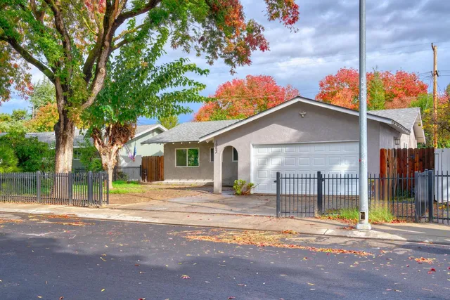 a front view of a house with a garden and tree