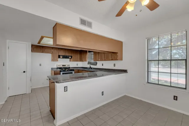 a kitchen with stainless steel appliances granite countertop a sink and a stove next to a window