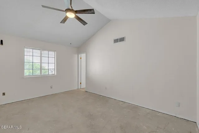 an empty room with windows and chandelier fan