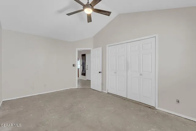 a view of an empty room and chandelier fan