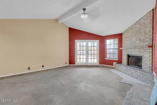 a view of an empty room with a fireplace and a window