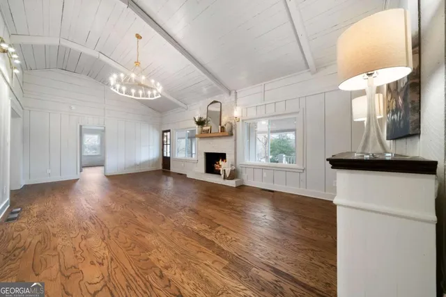 a view of a livingroom with a fireplace a chandelier and wooden floor