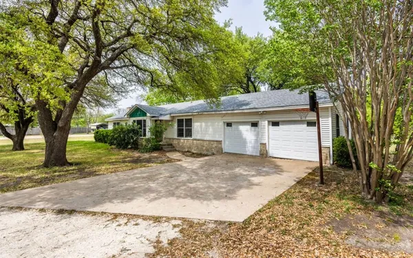 a view of a yard in front of a house with large tree