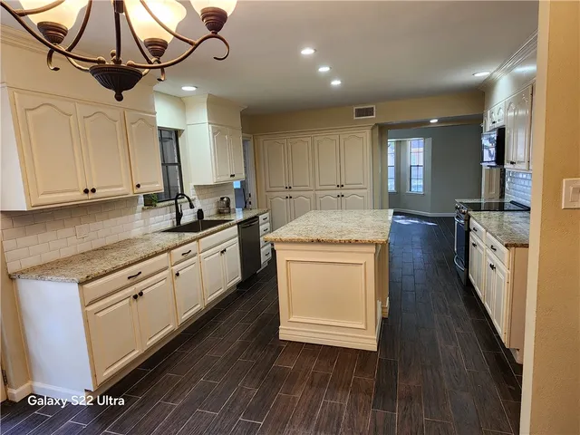 a kitchen with stainless steel appliances granite countertop a sink a stove and cabinets