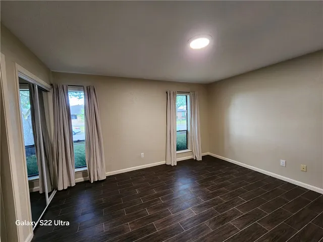 a view of an empty room with window and wooden floor