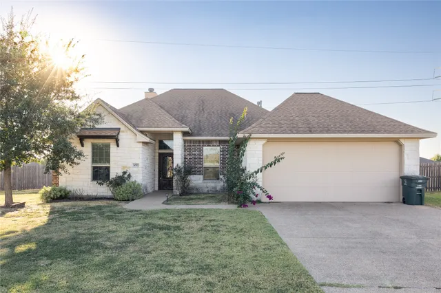 a view of a house with backyard and bushes
