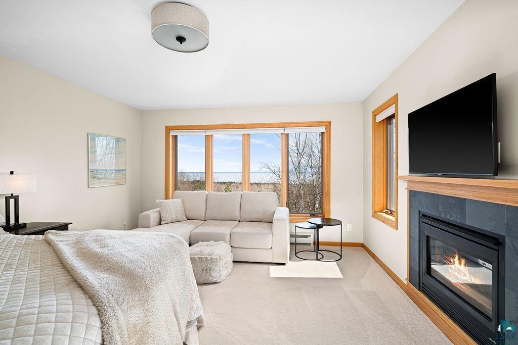 4856 Kingston Street Duluth, MN 55804 - Photo 31 of 88 Carpeted bedroom featuring large windows with wood trim, a built-in fireplace with a dark stone surround and wood mantel, and a flush-mount ceiling light fixture