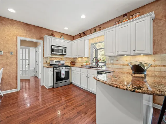 a kitchen with stainless steel appliances kitchen island granite countertop a refrigerator and a sink
