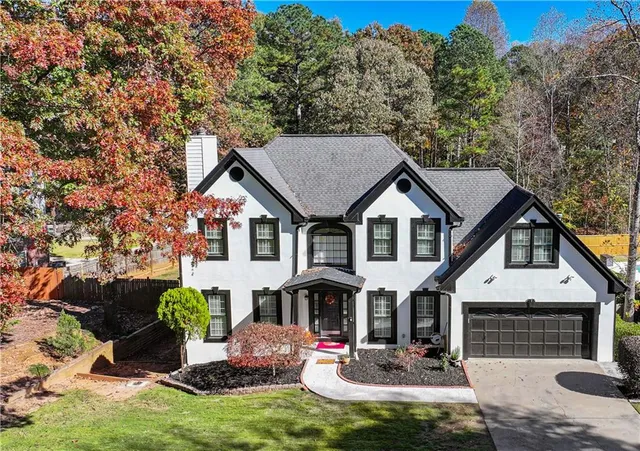 a front view of house with yard and trees in the background