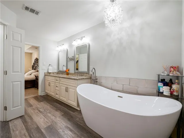 a bathroom with a tub a double vanity sink and a mirror