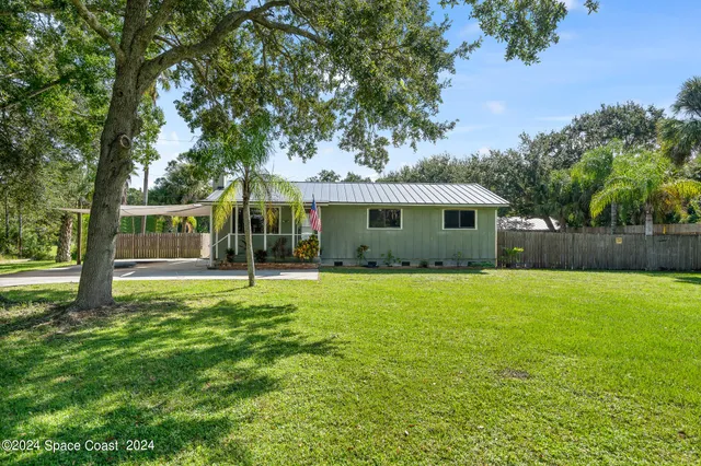 a view of a house with backyard and a tree