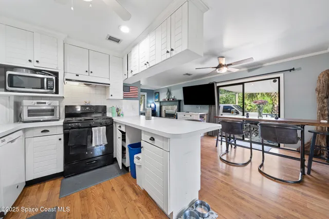 a kitchen with cabinets stainless steel appliances and wooden floor