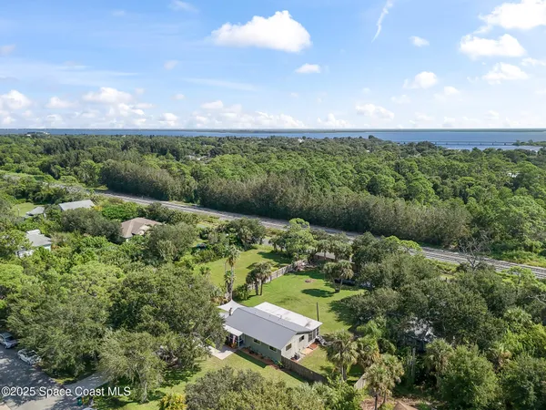 an aerial view of a houses with outdoor space and trees all around