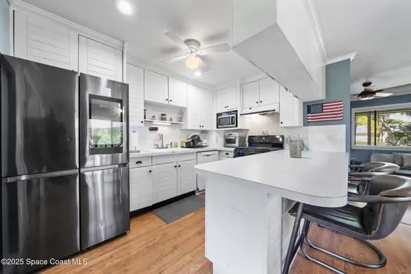 a kitchen with stainless steel appliances a stove a sink dishwasher a microwave oven with cabinets and wooden floor