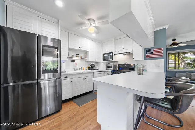 a kitchen with stainless steel appliances a stove a sink dishwasher a microwave oven with cabinets and wooden floor