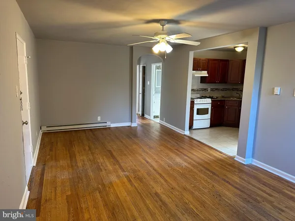 an empty room with kitchen view and wooden floor