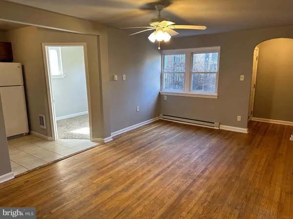an empty room with wooden floor chandelier fan and windows
