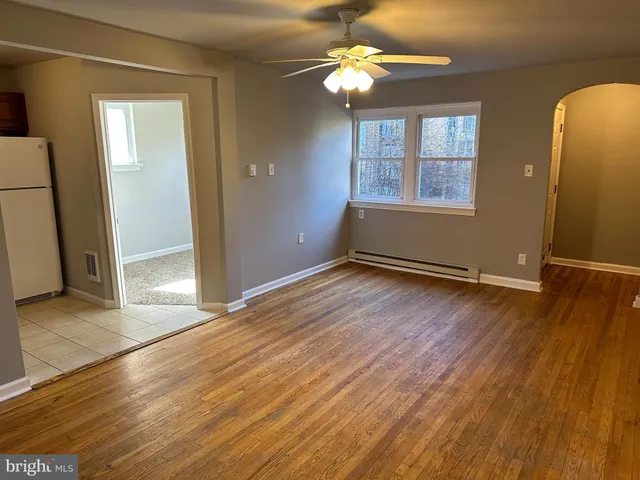 an empty room with wooden floor chandelier fan and windows
