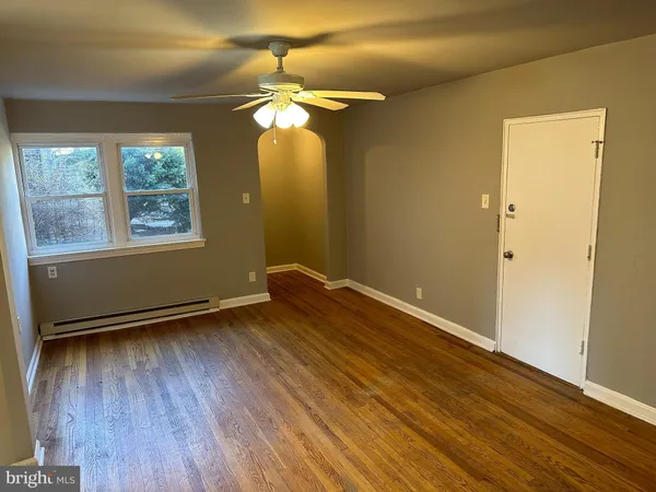 a view of an empty room with wooden floor and a window
