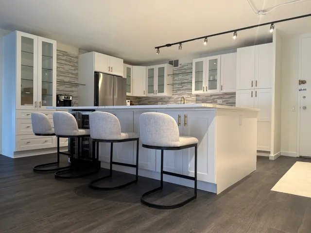 a kitchen with stainless steel appliances granite countertop a dining table chairs and granite counter tops