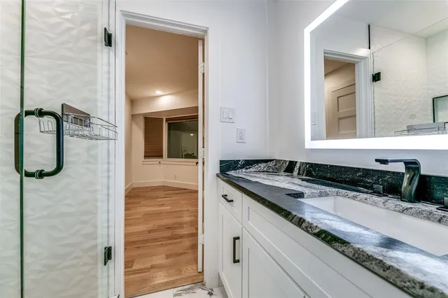 a bathroom with a granite countertop sink a mirror and shower