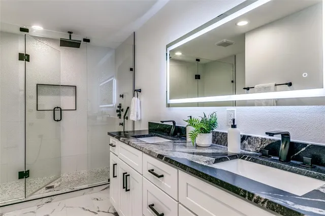 a bathroom with a granite countertop sink mirror and shower