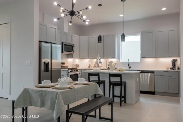a kitchen with kitchen island a dining table chairs stainless steel appliances and cabinets