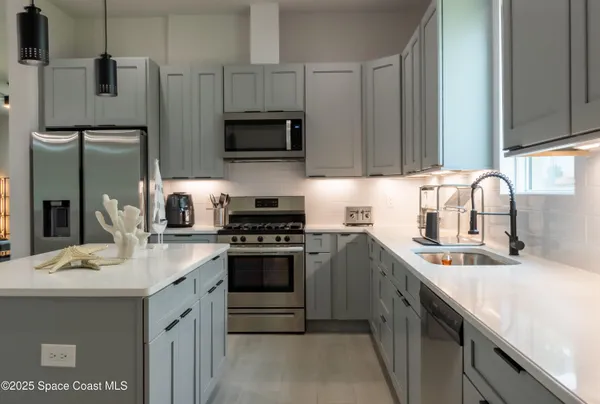 a kitchen with stainless steel appliances a sink a stove a microwave a sink and refrigerator