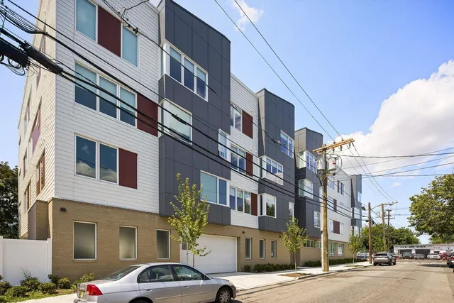 a front view of a building with lot of cars and trees