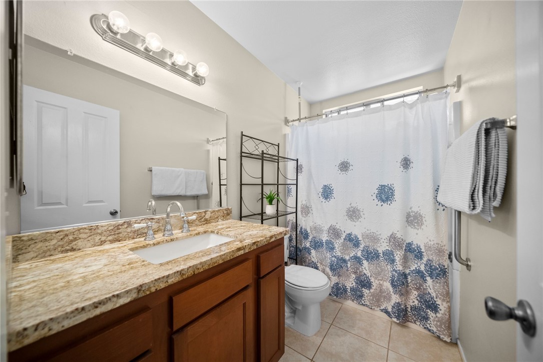 27879 Foxfire Street Menifee, CA 92586 - Photo 26 of 36 a bathroom with a granite countertop sink a toilet a mirror and shower