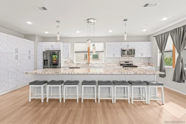 a large kitchen with kitchen island granite countertop lots of white cabinets appliances and furniture