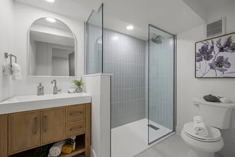 a bathroom with a shower sink vanity mirror and toilet