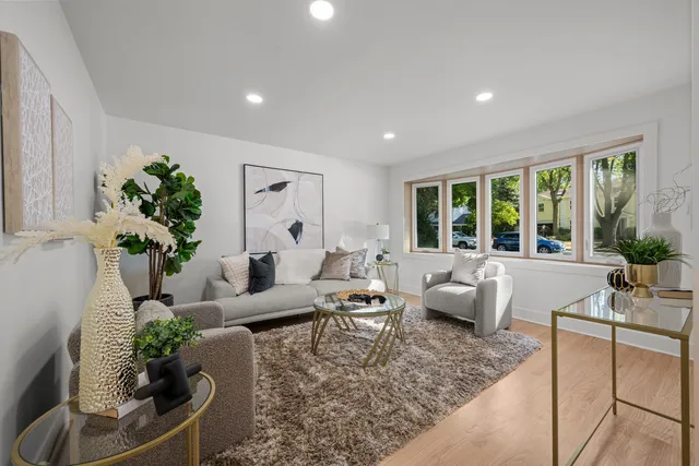 a living room with furniture large window and potted plants