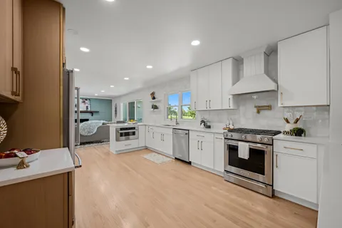 a kitchen with stainless steel appliances white cabinets a sink a stove a refrigerator and a oven