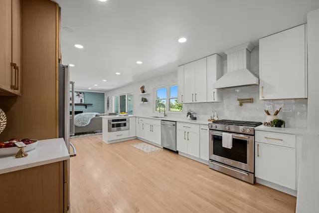 a kitchen with stainless steel appliances white cabinets a sink a stove a refrigerator and a oven