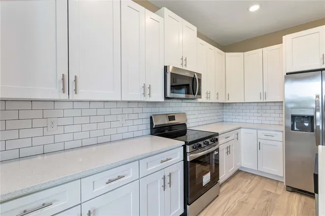 a kitchen with cabinets stainless steel appliances a sink and wooden floor