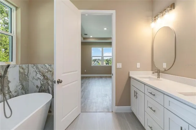 a en suite bathroom with a granite countertop tub double vanity sink and a mirror