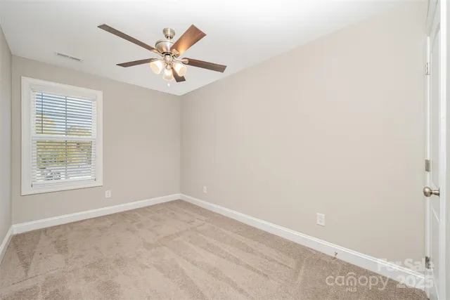 an empty room with window and ceiling fan
