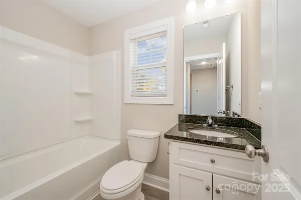 a bathroom with a granite countertop toilet a sink a mirror a bathtub and shower