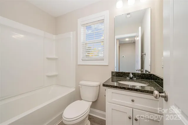 a bathroom with a granite countertop toilet a sink a mirror a bathtub and shower