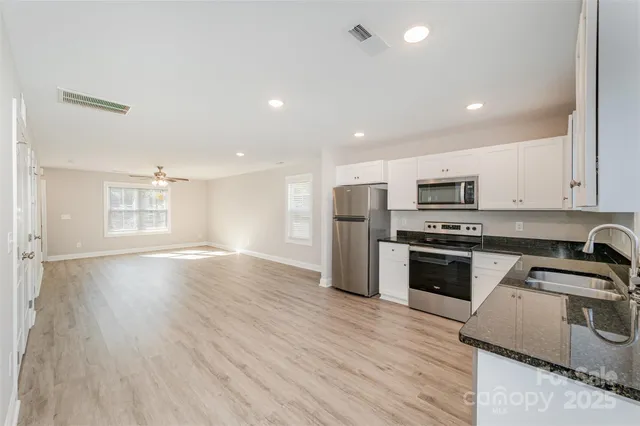 a kitchen with stainless steel appliances granite countertop a refrigerator a sink dishwasher a stove with wooden floors and cabinets