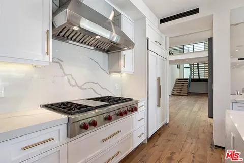 a large kitchen with kitchen island a large window a sink and stainless steel appliances