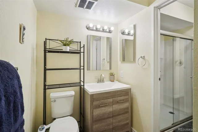 a bathroom with a granite countertop sink toilet a mirror a shower and vanity