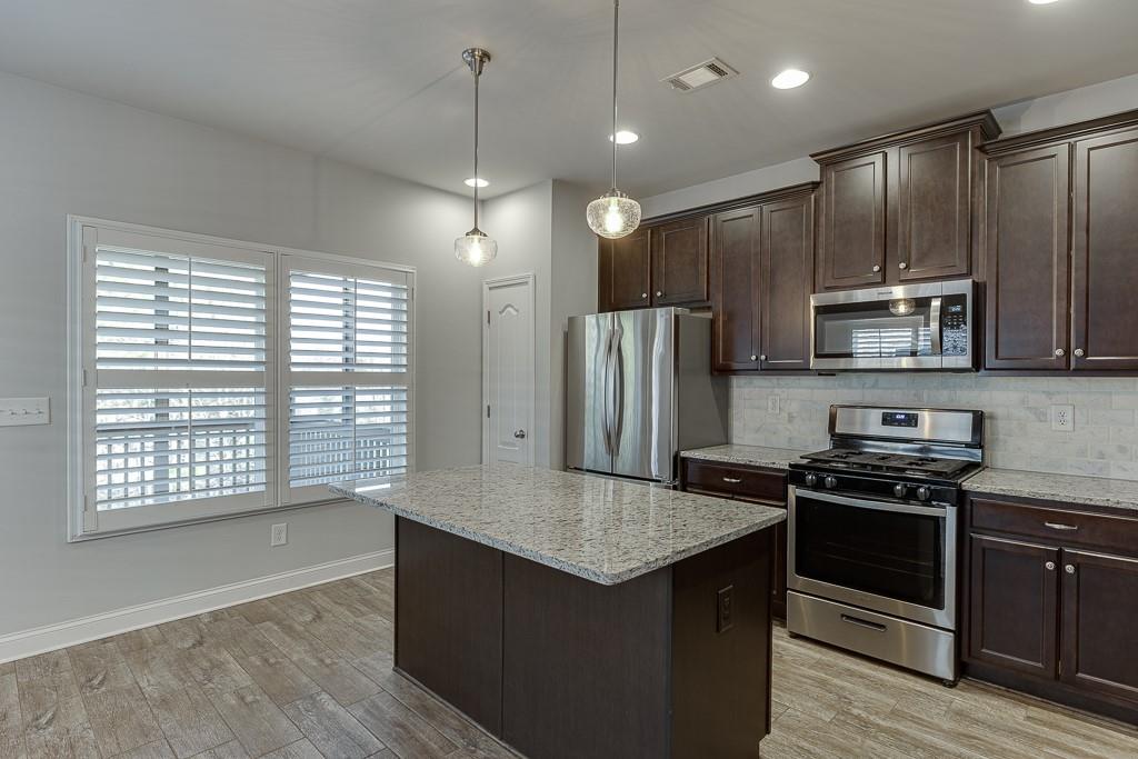 567 Lillian Way Jefferson, GA 30549 - Photo 14 of 80 a kitchen with stainless steel appliances granite countertop a refrigerator a sink a stove a microwave and wooden cabinets