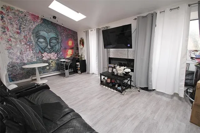 a living room with furniture a flat screen tv and a refrigerator